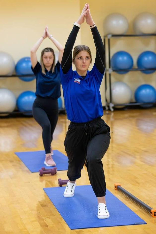 博彩平台推荐 students in a yoga class holding a yoga pose